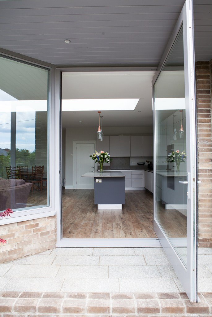 Opened pivot door with silver door frame - kitchen