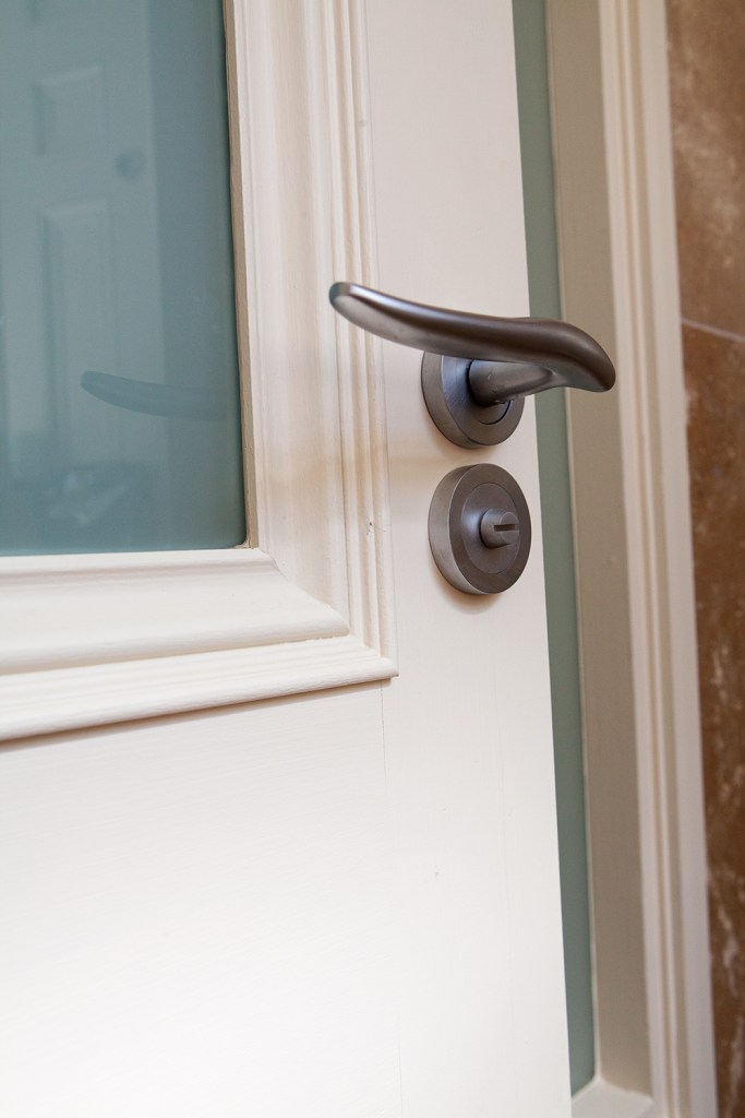 White door with white frame and casing - transom window - iron handlebar and key hole cylinder