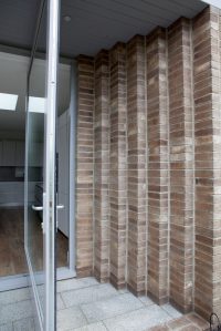 Open glass pivot door - brick step wall