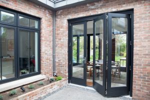 Bi-fold glass door with black frame and brick wall