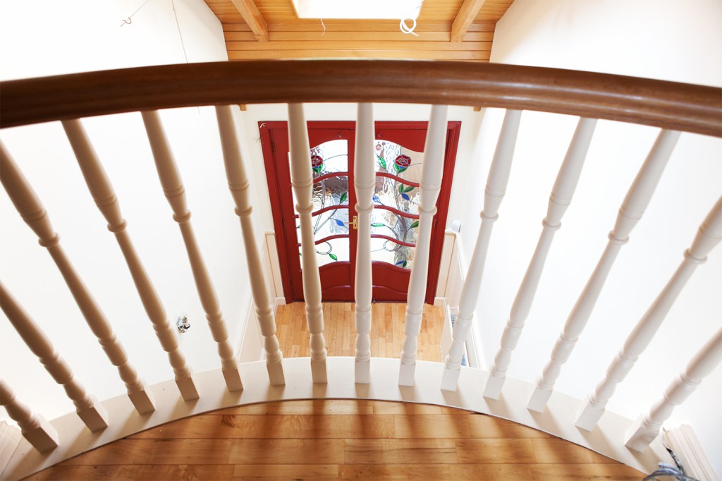 White baluster - wooden handrail - looking down at red door