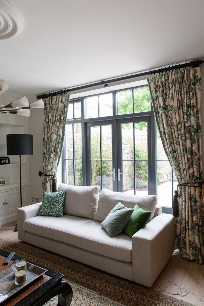 natural light - lounge area - couch - opened curtains - carpet - window with black frame and grille
