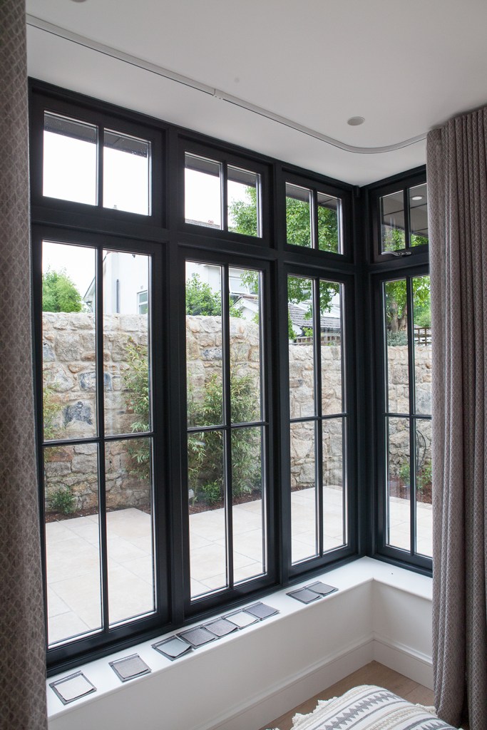 black window frame with black grille - white interior window sill - open sliding curtains - fanlight windows