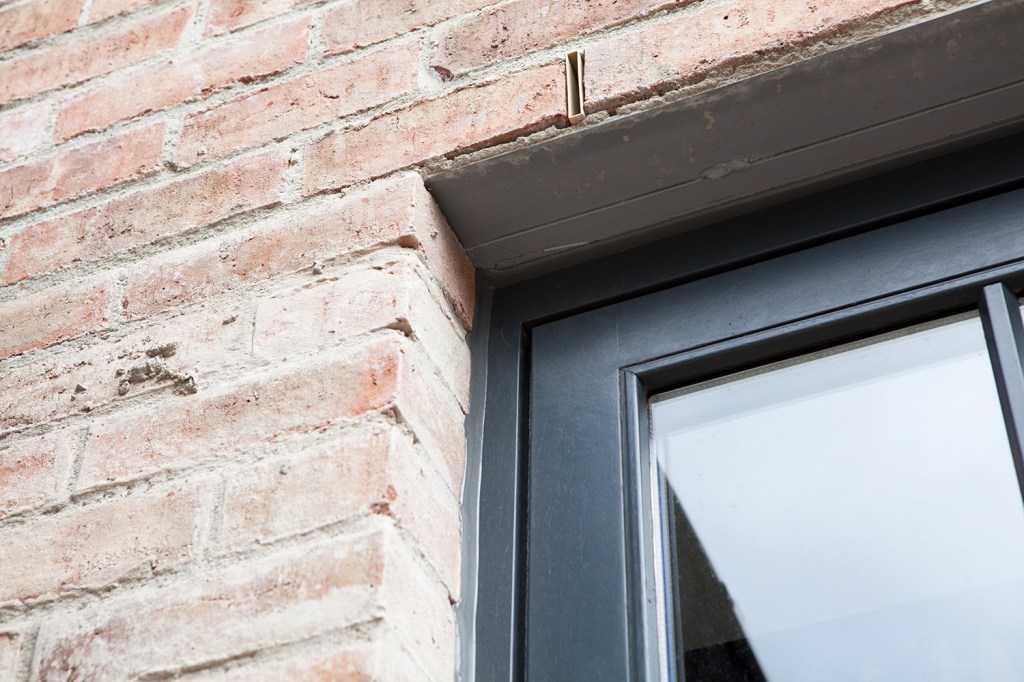 black window frame with silver and brick window casing - brick wall