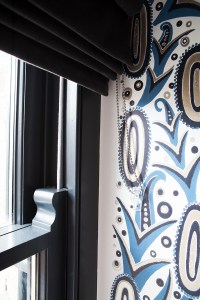 painted shapes on white wall in blue and black - open window blinds - black window frame - sliding double hung windows