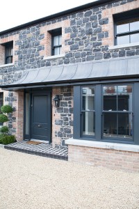 black stone and red brick wall house - black window frame - black front door with black and white checkered tile patio - gravel