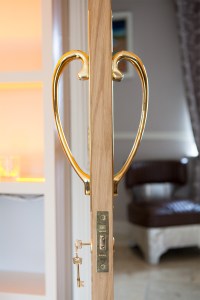 Golden door handle shaped in half hearts - golden key in key cylinder - open door - gold door hinges