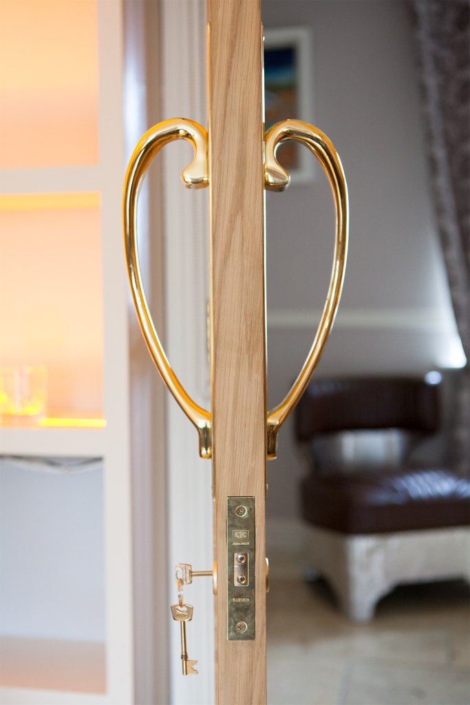 Golden door handle shaped in half hearts - golden key in key cylinder - open door - gold door hinges