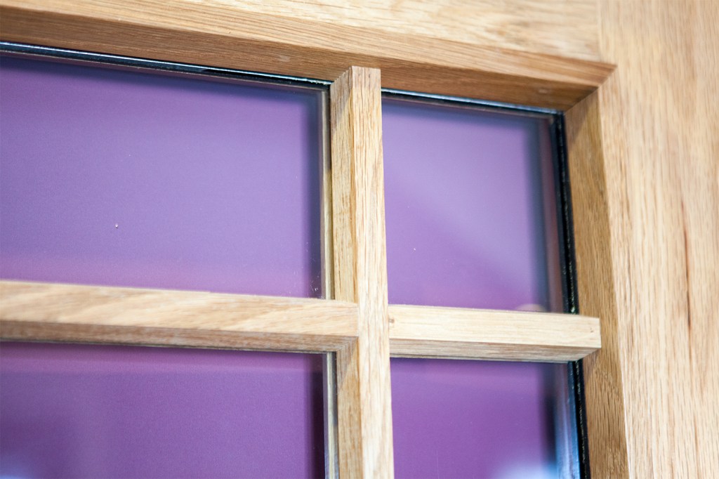 Close up of wooden window frame and grille with wooden casing - purple blind