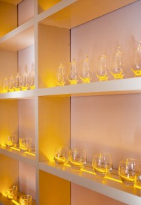 whiskey glasses in a lit up white cupboard - glasses in a row - white wooden open cupboard