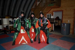 three men in sky diving suits - green and red sky diving suit