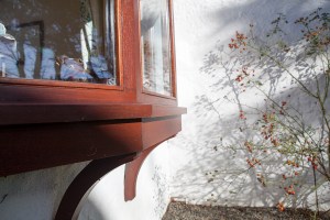 Close up of window sill - wooden window sill - wooden window frame - white wall - bushes