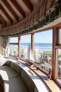 Curved seating - curved window wall - decorations on window sill - ceiling curtain skirts - view of ocean and landscape