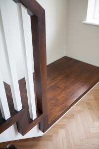 chocolate wood staircase landing - white wooden staircase baluster - dark wood stair tread - dark wood staircase string