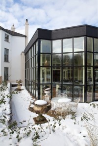 Snow outside with garden table and chairs - black window building - black window frame and grilles - wall windows