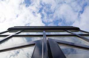 View of clouds with the top of glass building - black window and door frame