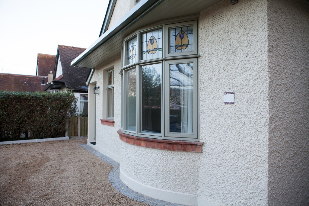 Curved window with red brick window sill - green window frame and casing - stained fanlight glass window