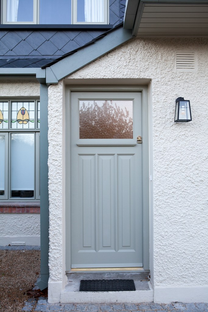 Light mint green door with panels and transom window - lantern light hanging on wall