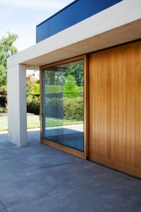 Sliding door made out of glass - wood frame and casing - sheeted wood wall - outside view - corner sliding door