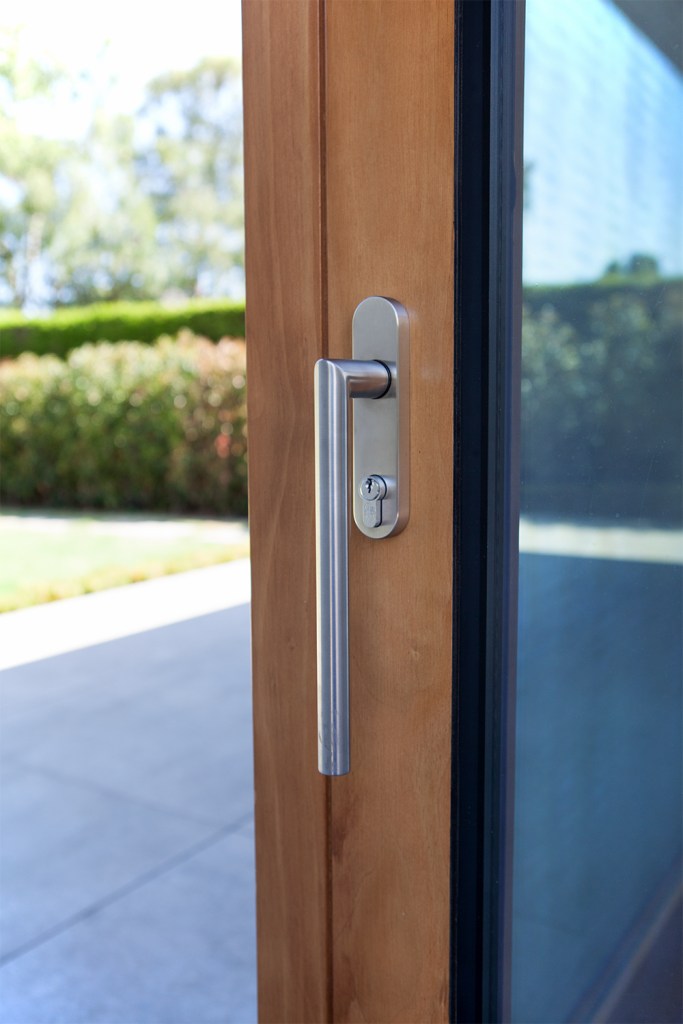 Silver long door handle - wooden door frame - door with window - corner of door frame and casing