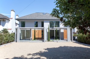 Gravel front yard - wall windows - wood sheeted front double door - cement pillars