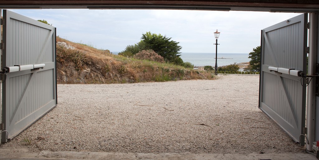 Double barnyard style doors - opened - hydraulic door opener and closer - gravel - view of ocean and landscape