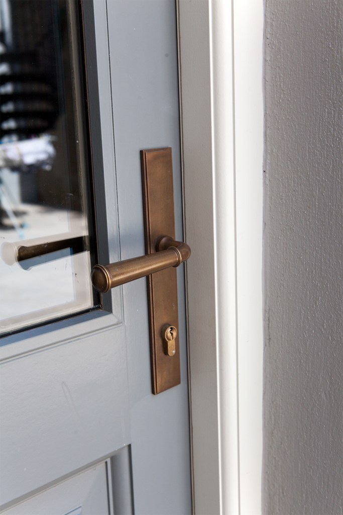 Bronze door handle on a grey transom door with a white door frame