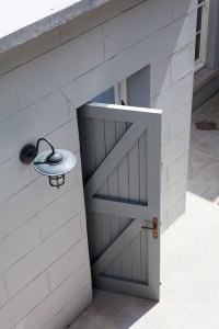 Simple grey wooden door with bronze handle - grey wall with black wall lantern light