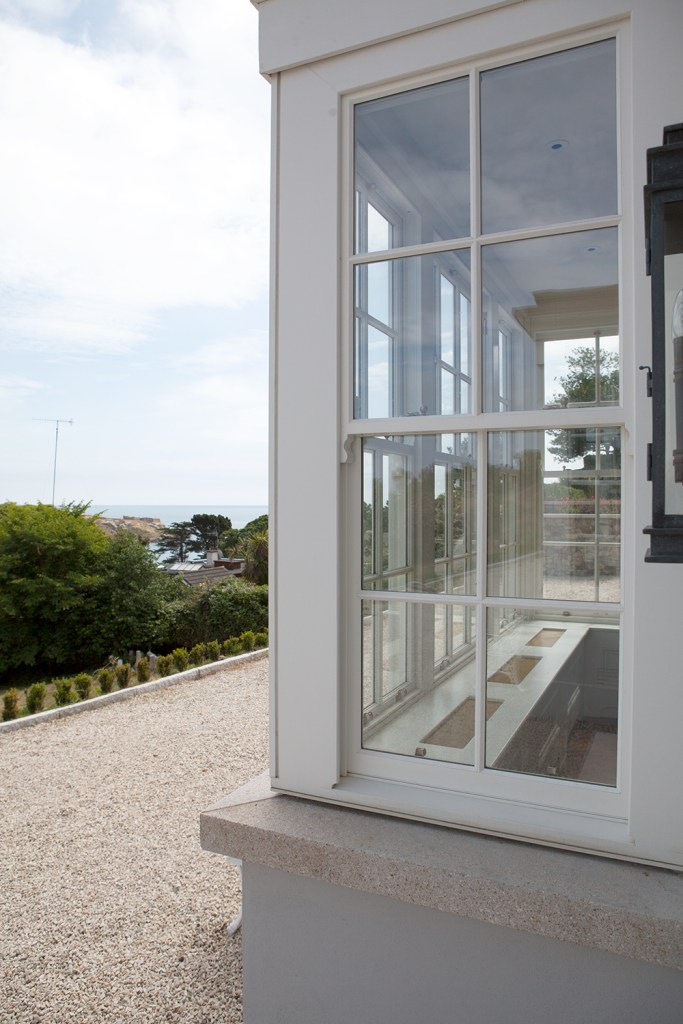 Double hung corner window with white frame and white grills - outside window sill - gravel