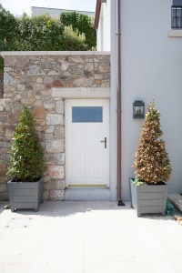 Transom white door with stone wall frame and two small pot plant tree's