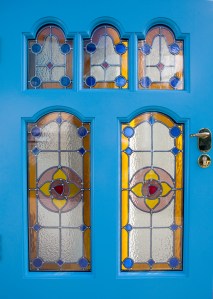 Door with blue and yellow stained glass in window - blue frame around stained windows - carved frame