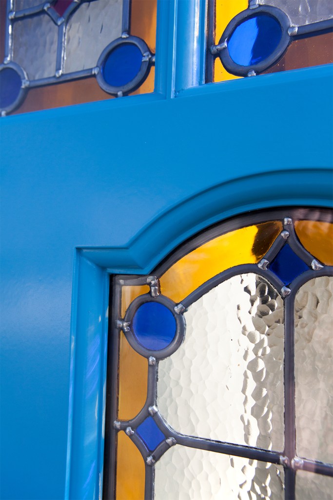 Stained glass window in door - blue door - blue carved window frame - blue and yellow stained windows