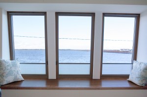 inside window sill with scatter pillows and view outside of sea through window - wooden tread - wooden window frame