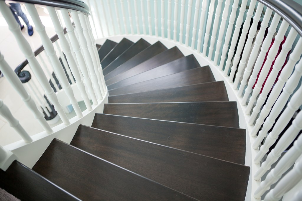 Chocolate color wood staircase - dark wood stair tread - spiral down - spiral stairs - white wood baluster - white stringer