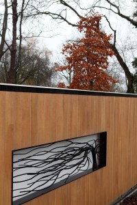 Side view os sheeted gate with metal tree and branches inside of gate - black metal gate frame - orange tree in background