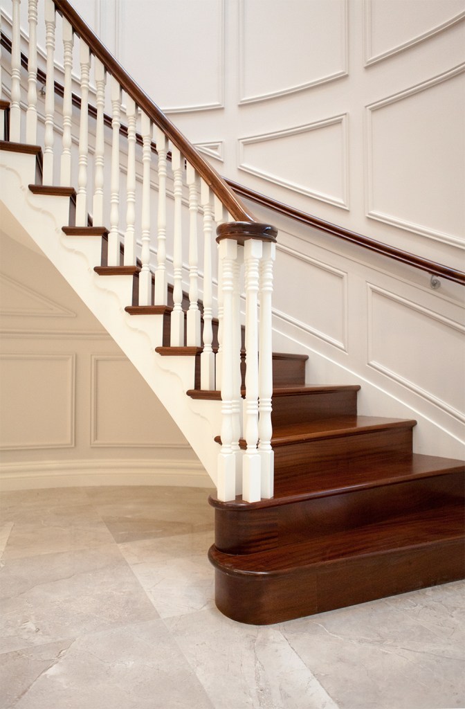 First step of staircase - dark wood stair tread with white baluster and dark wood handrail