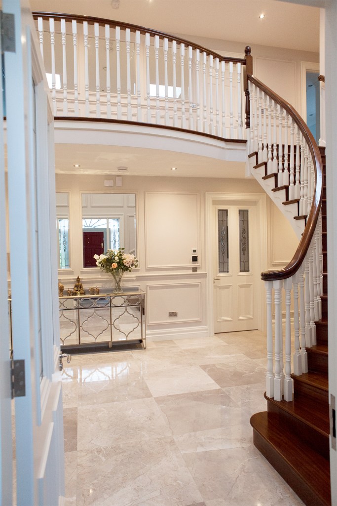 Entrance to house - staircase starting step - white stair baluster and dark wood handrail - inside balcony - white tiled floor