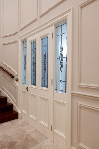 Stained glass door with stained glass sidelites windows - white wood panel wall - side view