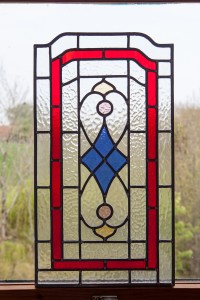 Whole view of red and blue stained glass with black grilles - leaning against clear window
