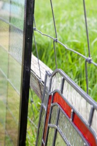 Stained glass leaning against fence - green grass