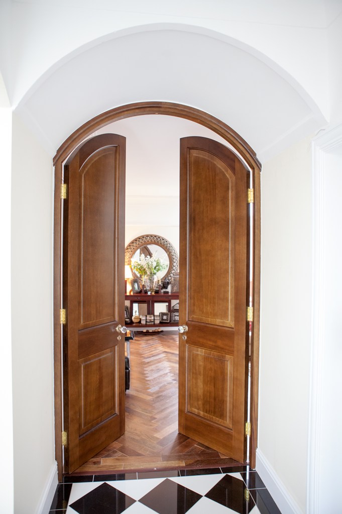 Arched double swing door with arched wood door frame and white door casing - gold door hinges