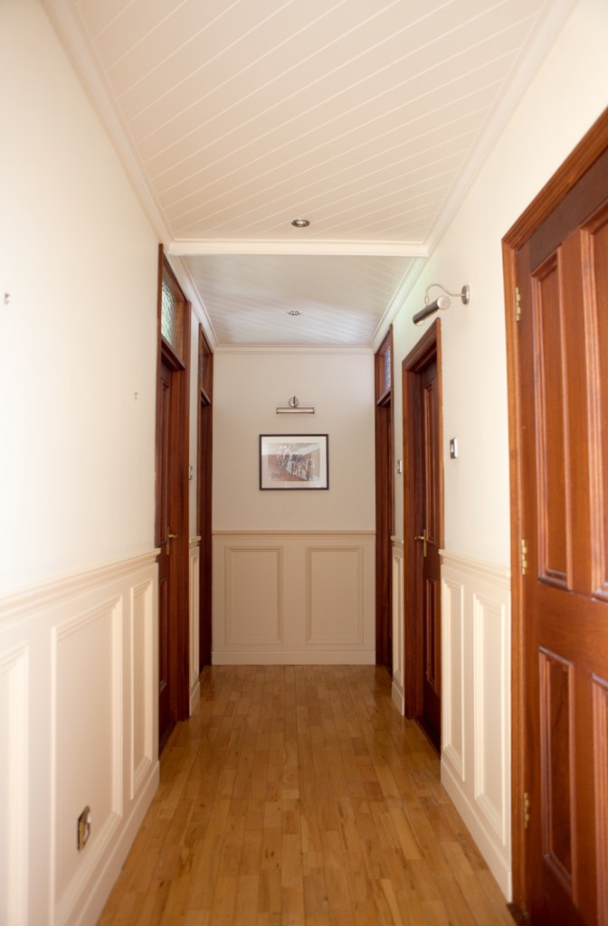 Hallway view with doors to the side - wooden doors - wooden door frames - half wall white panel - white ceiling - transom door