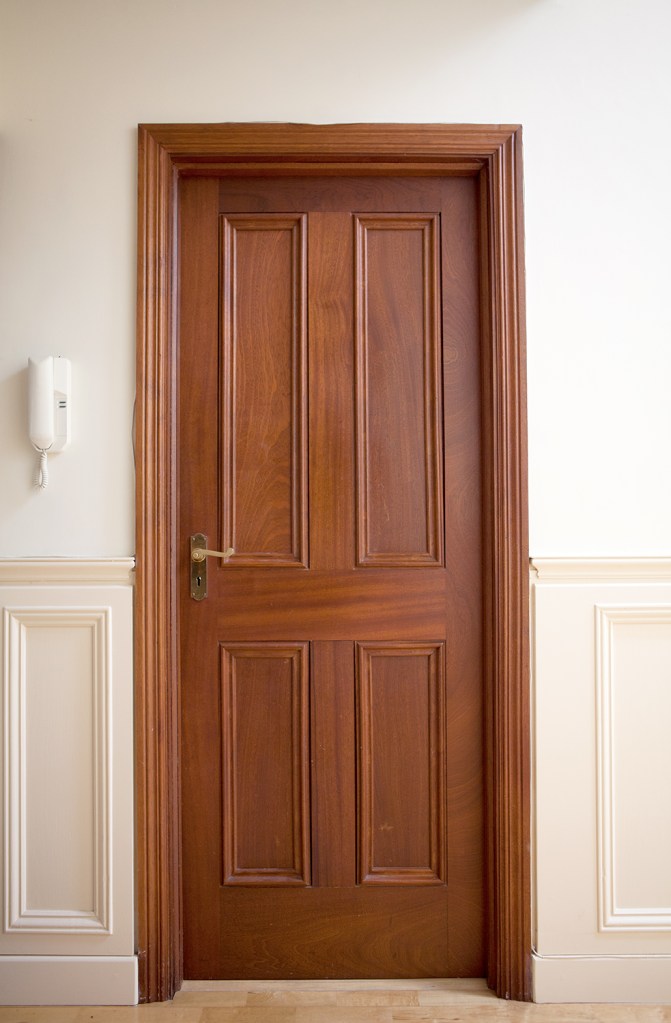 Interior wooden door with wood panel and wood door frame - bronze door handle - half wall panel - wall phone
