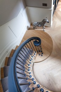 Zebra decor at foot of stairs - curved stairs - curved staircase handrail - wooden stair tread with carpet - right hand turnout handrail detail