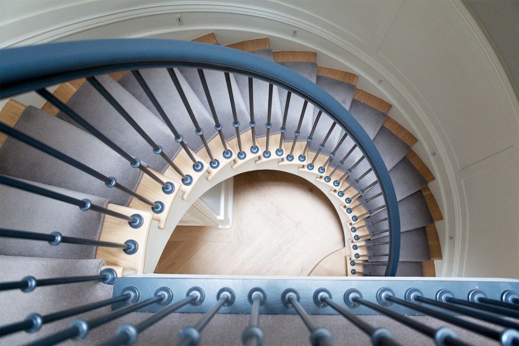 Spiral staircase - view from top - iron balustrade - wooden tread with carpet - curved staircase