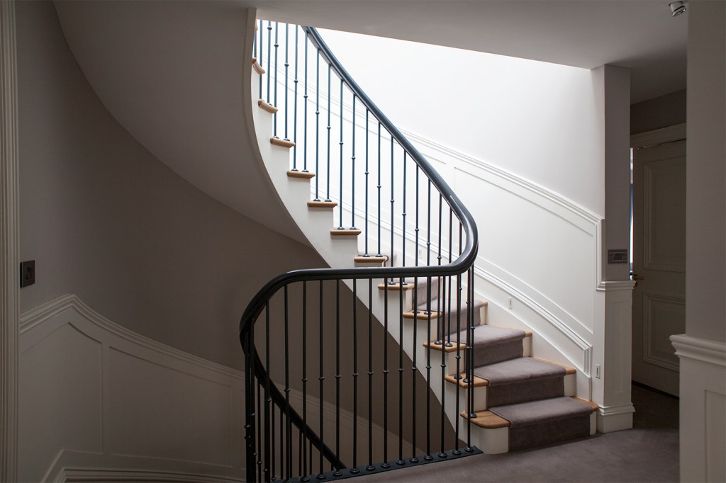 Curved staircase - curved iron balustrade and handrail - carpet on wooden tread