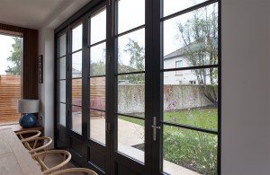 View through transom door - stacker doors with black frame and grilles - backyard view - silver door handle