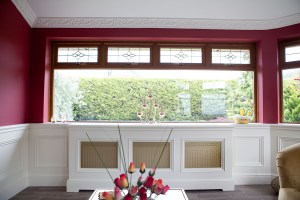 Window above radiator cover - clerestory windows with details - half white wall and half painted wall - closed roses on coffee table - clear window