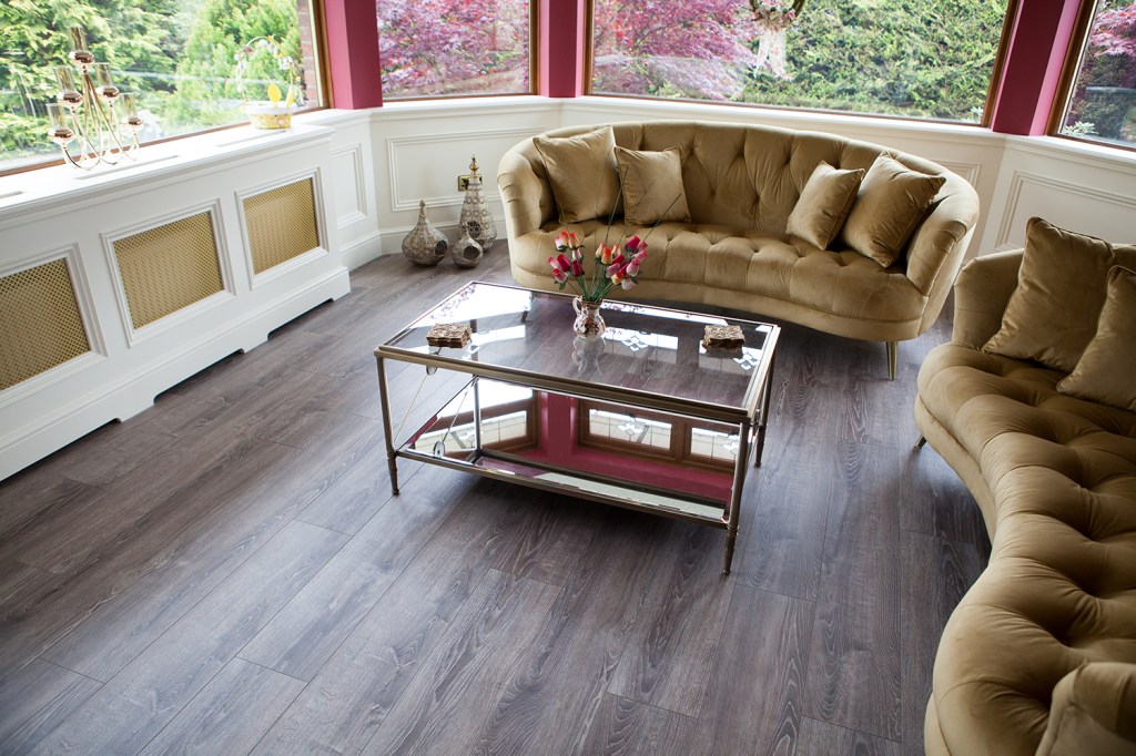Lounge area with curved windows allowing natural light - lounge set - coffee table - laminated floors - white radiator cover - red walls