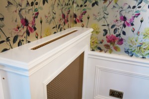 Top of radiator cover with flower wallpaper on the walls - white radiator cover with bronze details